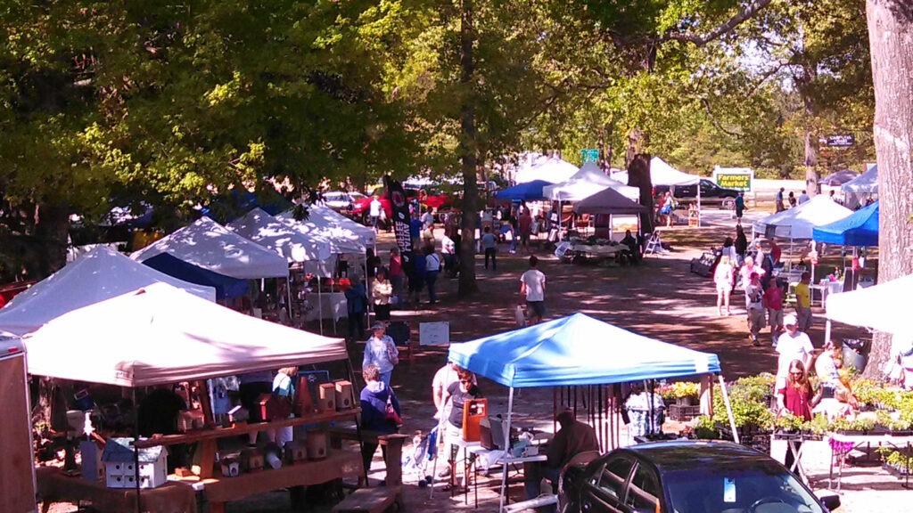 Market stalls and shoppers under the trees